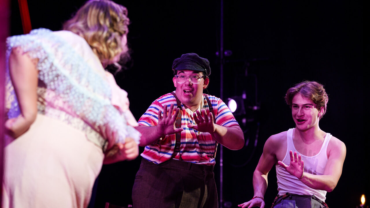 3 student actors laughing on stage